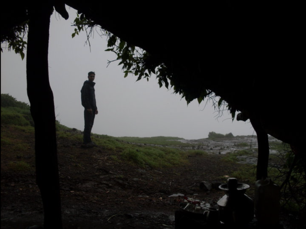 Husain looking out from the cave at Harishchandragad — the mist outside tells the whole story