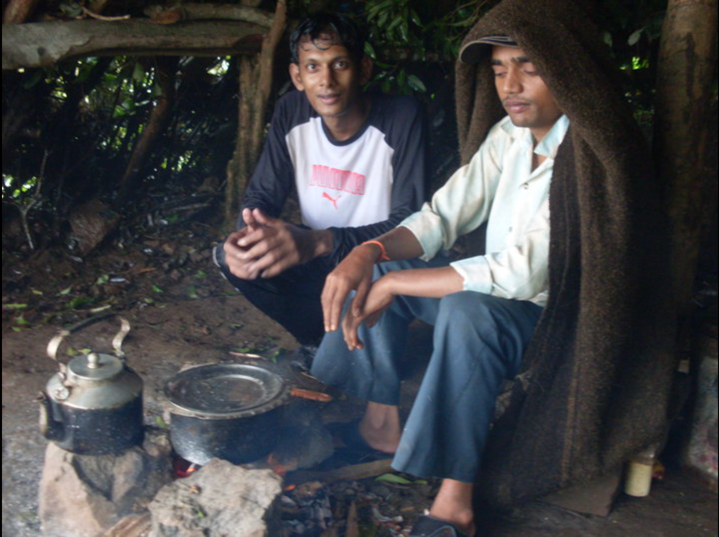 Two men sitting by the fire at the villager's hut on the Harishchandragad trek — the kindest strangers
